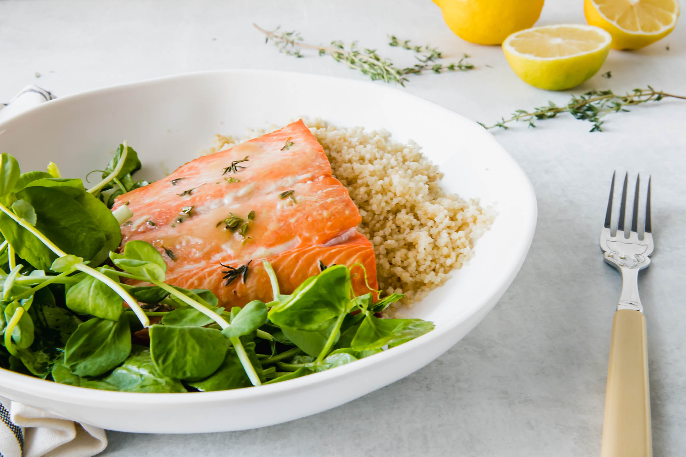 Salmon entree on a bed of couscous and fresh salad greens.